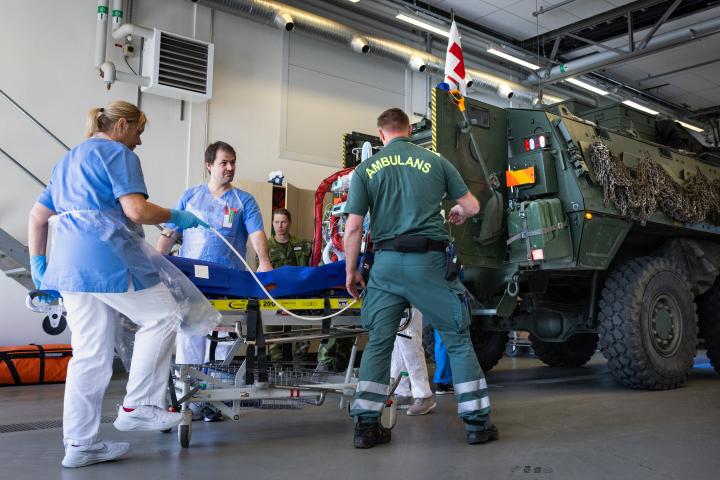 Ambulanspersonal som tar hand om en skadad patient på en bår.