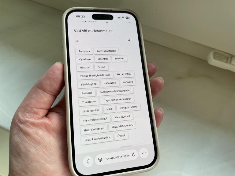 Mobiltelefon i en hand som visar att man gör en digital felanmälan på Mina sidor.