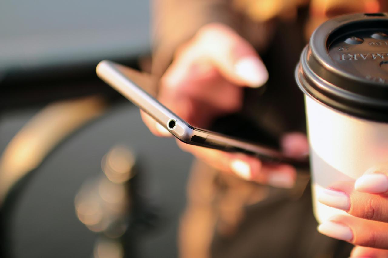 Tittar på mobilen med en take away kaffe