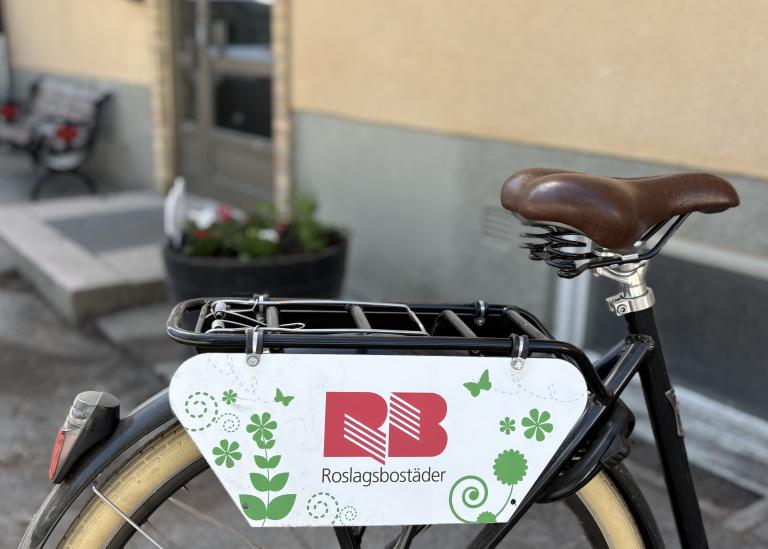 Cykel med en vit skylt med Roslagsbostäders logga på.